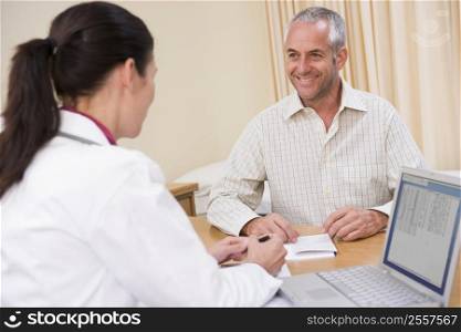 Doctor with laptop and man in doctor&acute;s office smiling