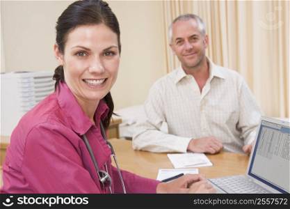 Doctor with laptop and man in doctor&acute;s office smiling