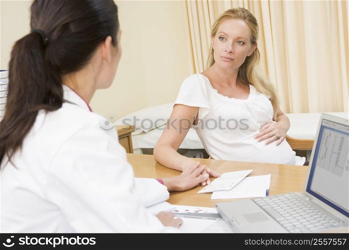 Doctor with laptop and pregnant woman in doctor&acute;s office
