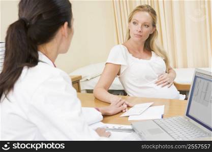 Doctor with laptop and pregnant woman in doctor&acute;s office