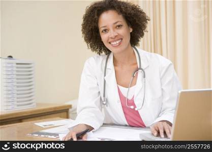 Doctor with laptop in doctor&acute;s office smiling