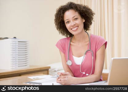 Doctor with laptop in doctor&acute;s office smiling