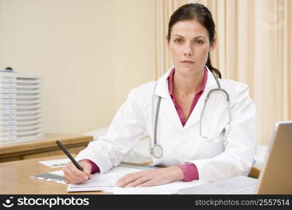 Doctor with laptop writing in doctor&acute;s office