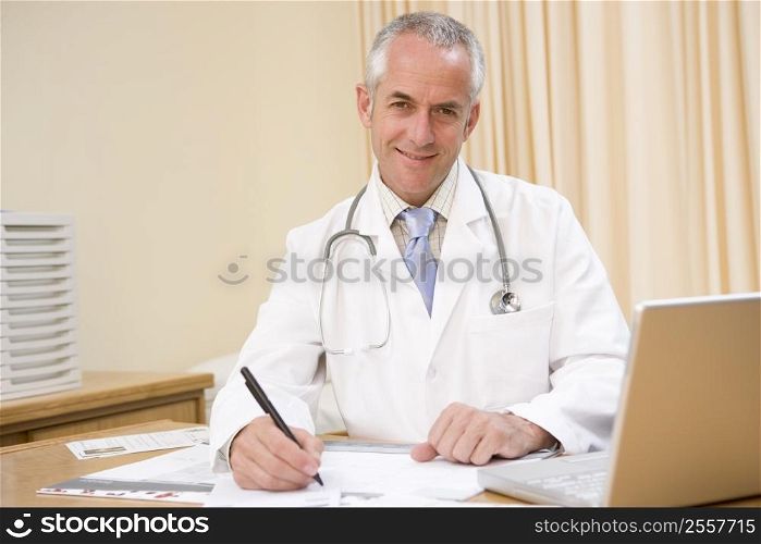 Doctor with laptop writing in doctor&acute;s office