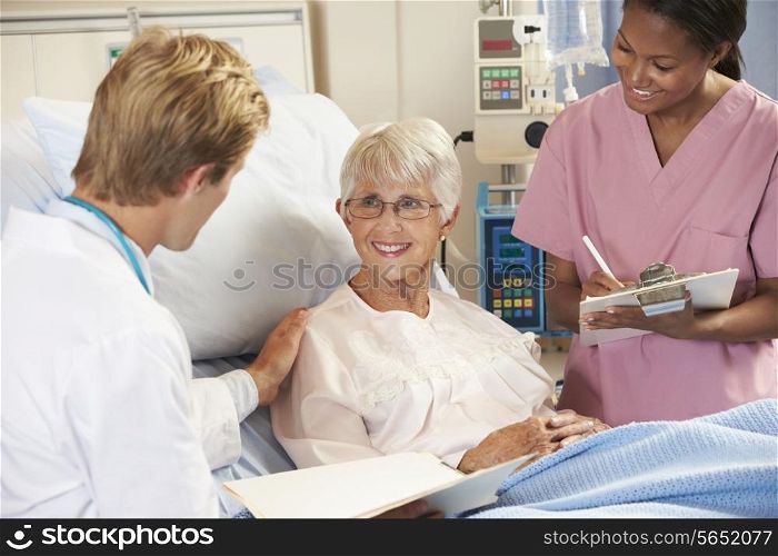 Doctor With Nurse Talking To Senior Female Patient In Bed