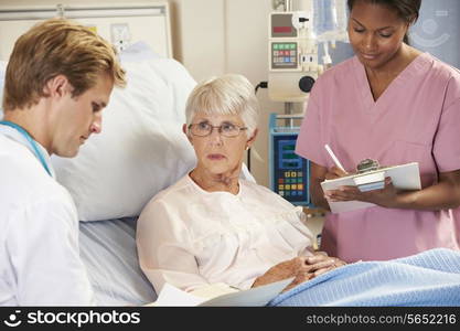 Doctor With Nurse Talking To Senior Female Patient In Bed