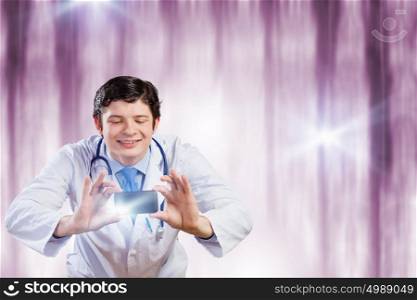 Doctor with photo camera. Young funny doctor taking photos with mobile phone camera