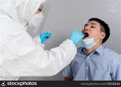doctor with PPE suit test coronavirus(covid-19) to young man by mouth swab