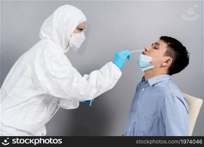 doctor with PPE suit test coronavirus(covid-19) to young man by nasal swab