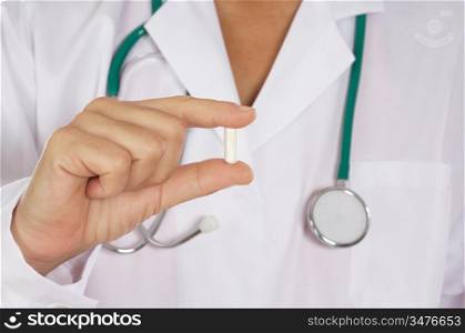 Doctor with uniform holding one pill in the hand