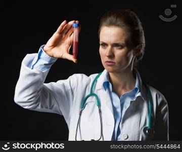 Doctor woman looking on test tube on black background