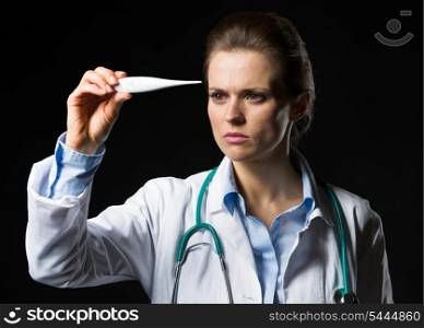 Doctor woman looking on thermometer isolated on black