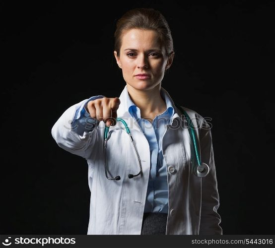 Doctor woman pointing in camera isolated on black