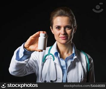 Doctor woman showing medicine bottle on black background