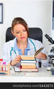 Doctor woman sitting in cabinet with stack of books&#xA;