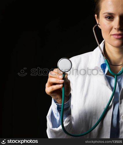 Doctor woman using stethoscope isolated on black