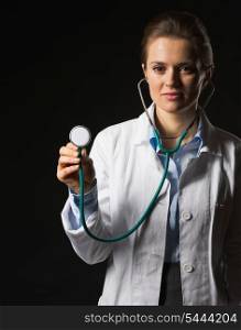 Doctor woman using stethoscope on black background