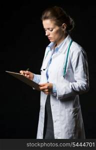 Doctor woman writing in clipboard isolated on black