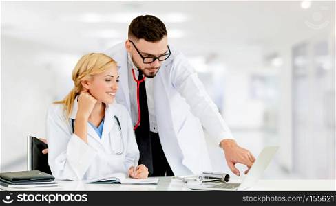 Doctor working with laptop computer at the office while having discussion with another doctor in the hospital. Medical healthcare and doctor service.