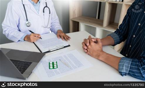 doctor working with patient taking notes with clipboard and discussing something in his medical office, health care and people concept