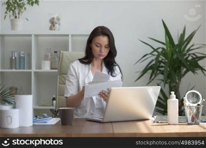 Doctor working with test results and computer at clinic. Filling patient medical record