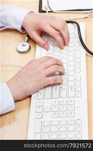 doctor works on white PC keyboard close up
