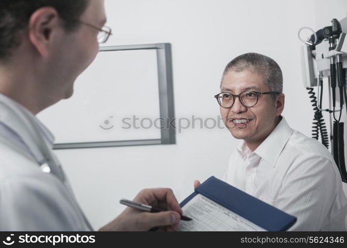 Doctor writing on medical chart with a smiling patient