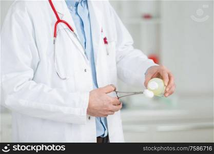 doctors hands holding a surgical clamp with swab