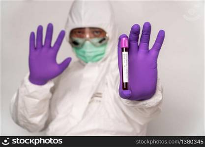 Doctors in the protective suits and masks are holding a positive blood test result for new rapidly outbreaking Coronavirus and showing stop hands for stop coronavirus (COVID-19) by a stay at home.