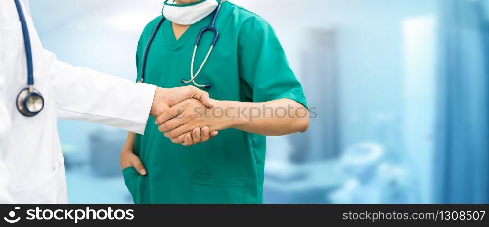 Doctors shaking hands with surgeon, standing in hospital background. Medical people teamwork and collaboration.