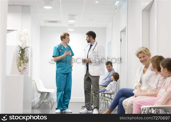 Doctors talking while patients waiting in corridor at hospital