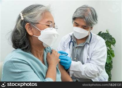 Doctors wear medical masks and vaccinated to senior women patients for the prevention of coronavirus and flu. Concept of immunization from inoculation