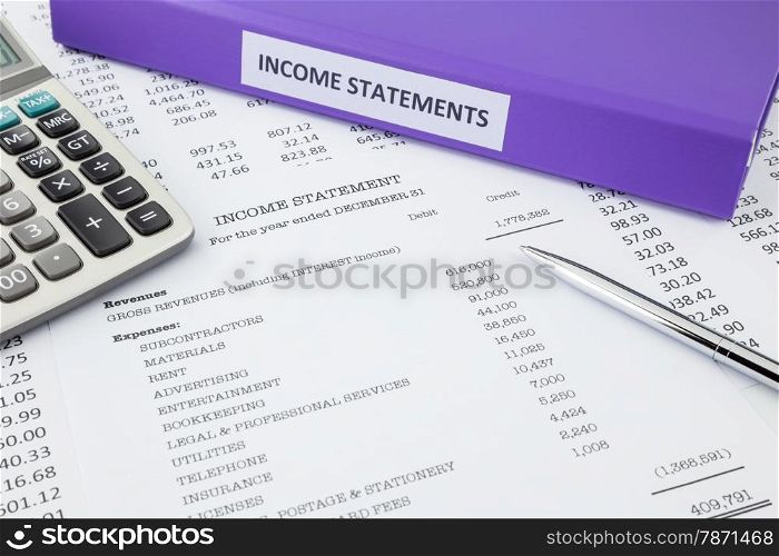 Document binder and income statement reports with detail list of revenues and expenses, pen pointing at credit revenues, concept for business accounting