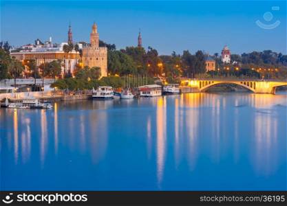 Dodecagonal military watchtower Golden Tower or Torre del Oro and bridge Puente San Telmo during evening blue hour, Seville, Andalusia, Spain