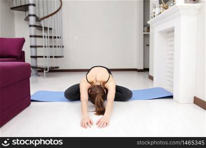 Does yoga exercises on mat on the floor. Young woman with slim body shape in sportswear have fitness day indoors at home. Does yoga exercises on mat on the floor. Young woman with slim body shape in sportswear have fitness day indoors at home.
