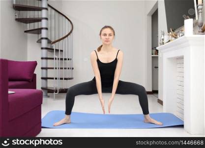 Does yoga exercises. Young woman with slim body shape in sportswear have fitness day indoors at home. Does yoga exercises. Young woman with slim body shape in sportswear have fitness day indoors at home.