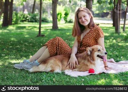 dog in the family - beautiful corgi fluffy on green lawn with girls