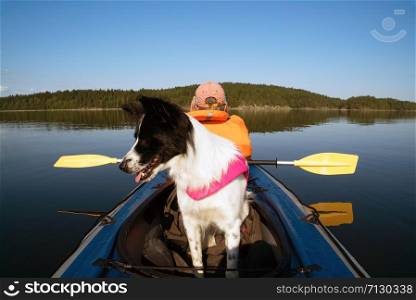 Dog sitting in the boat .lake Ladoga.Karelia,Skerries. The owner and the dog in a life jacket floating in a kayak boat.