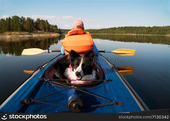 Dog sitting in the boat .lake Ladoga.Karelia,Skerries. The owner and the dog in a life jacket floating in a kayak boat.