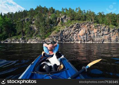 Dog sitting in the boat .lake Ladoga.Karelia,Skerries. The hostess and the dog are sailing in a kayak boat near the rocky shore.