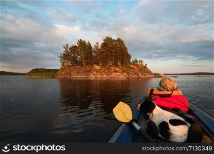 Dog sitting in the boat .lake Ladoga.Karelia,Skerries. The mistress and the dog are in a kayak boat near the island .