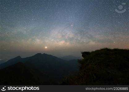 Doi Tung, Chiang Rai, Thailand with mountain hills, the milky way with bright stars on blue sky at night. Natural universe space landscape background. It is the galaxy that contains our Solar System