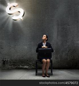 Dollar concept. Young businesswoman sitting on chair and looking at dollar symbol above