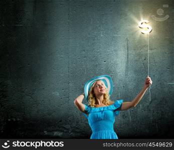 Dollar concept. Young pretty lady in blue hat and dress holding balloon