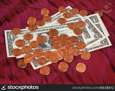 Dollar notes and coin, United States over red velvet background. One Dollar banknotes and One Cent coin money (USD), currency of United States over crimson red velvet background