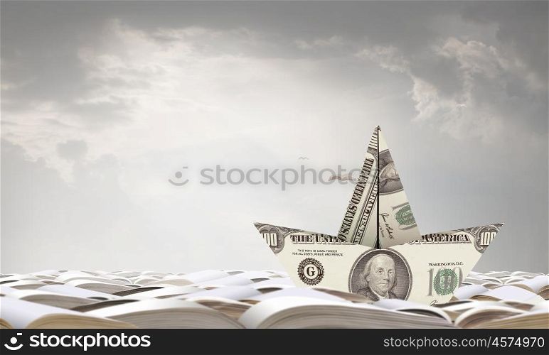 Dollar paper boat. Ship of dollar banknote floating on books