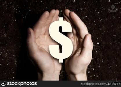 Dollar symbol in hands. Dollar sign in male palms on soil background