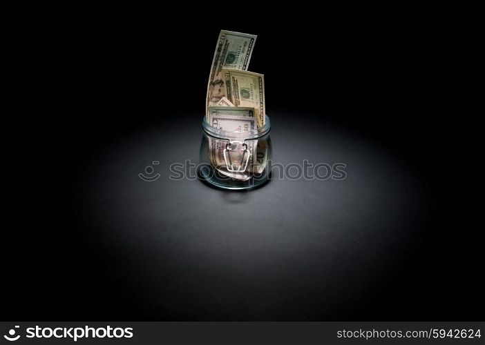 Dollars in glass jar on black
