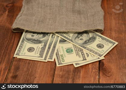 dollars with burlap sack on wooden background