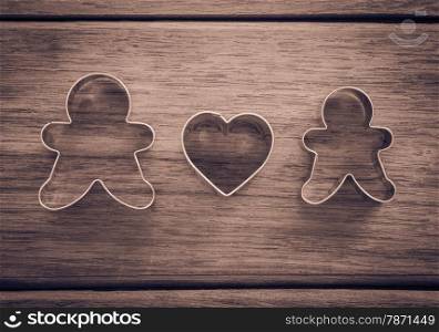 Dolls and heart shape of cookie cutters place on wood background with vignette, retro and sepia tone image, happy wedding anniversary and valentine&rsquo;s day symbol